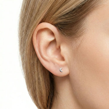 Oreille féminine avec boucle d'oreille petite lune en argent, bijoux minimalistes